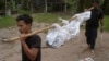 Workers carry a dead body in Songkhla province, southern Thailand, May 1, 2015. Police in Thailand found dozens of shallow graves in an isolated mountain area believed to have been used a trafficking camp.