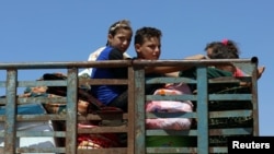 Anak-anak menaiki sebuah truk bersama barang bawaan di Deraa, Suriah, 22 Juni 2018.
