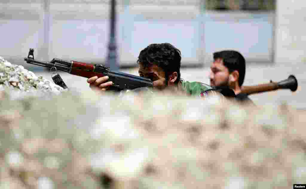 Özgür Suriye Ordusundan askerler Halep'te sokaklardaki barikatların arkasında siper alırken,13 Ağustos 2012