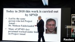 Waziri Mkuu wa Israeli, Benjamin Netanyahu atembea mbele ya bango lenye picha ya mwanasayansi wa masuala ya nyuklia wa Iran Mohsen Fakh-rizade. Aprili 30, 2018. 