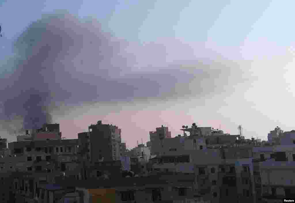 Smoke rises behind building from the site of an explosion in Beirut's southern suburbs, August 15, 2013.