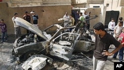 People inspect a car destroyed after a bomb attached to it exploded in Basra, Iraq's (File)