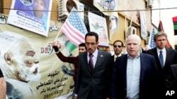 Le sénateur John McCain (à droite) et Abdul Hafiz Ghoqa, porte-parole du Conseil national de transition