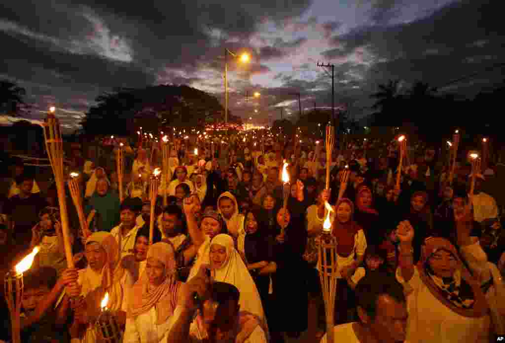Philippine Muslim women carry torches a rally south of Manila to call for a peaceful resolution to the fighting between Malaysian forces and a Philippine armed group in Borneo, March 6, 2013.