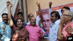 Teman-teman Kulbhushan Jadhav menyambut gemnbira perintah Mahkamah Tertinggi PBB (International Court of Justice) agar Pakistan tidak mengeksekusi perwira Angkatan Laut India ini, di dekat potret Jadhav di Mumbai, India, Kamis, 18 Mei 2017. (Foto: dok).