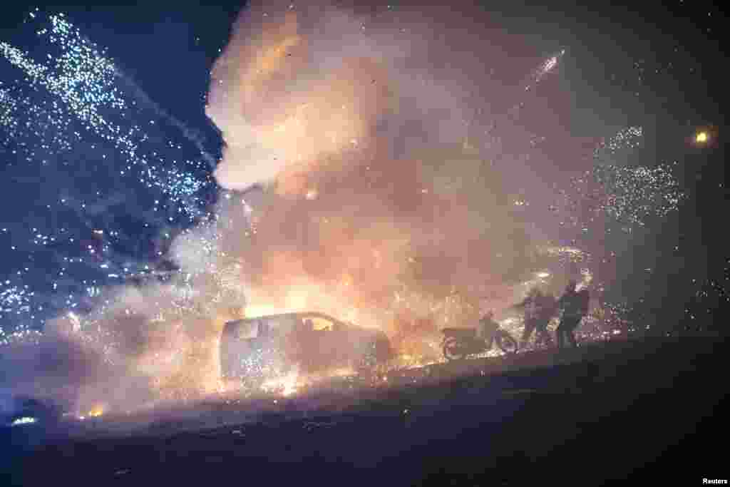 Firefighters try to control a blaze after a fireworks-laden hot-air balloon ignited while next to a car during the closing ceremony of the Tazaungdaing Festival at Taunggyi, in Myanmar's northeastern Shan State, Nov. 15, 2016.