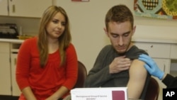 Penyintas Meningococcal meningitis dan pendukung vaksinasi Leslie Meigs memperhatikan saudara laki-lakinya Andrew (18), seorang mahasiswa di Texas, sedang divaksinasi Bexsero(R), vaksin meningitis grup B. (Foto:dok)