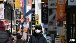 一位戴口罩的韩国女性走在首尔购物区街头。
