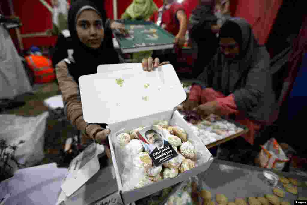 A supporter of deposed Egyptian President Mohamed Morsi shows a box of baked sweets with a picture of Morsi on top of it, Cairo, August 6, 2013.