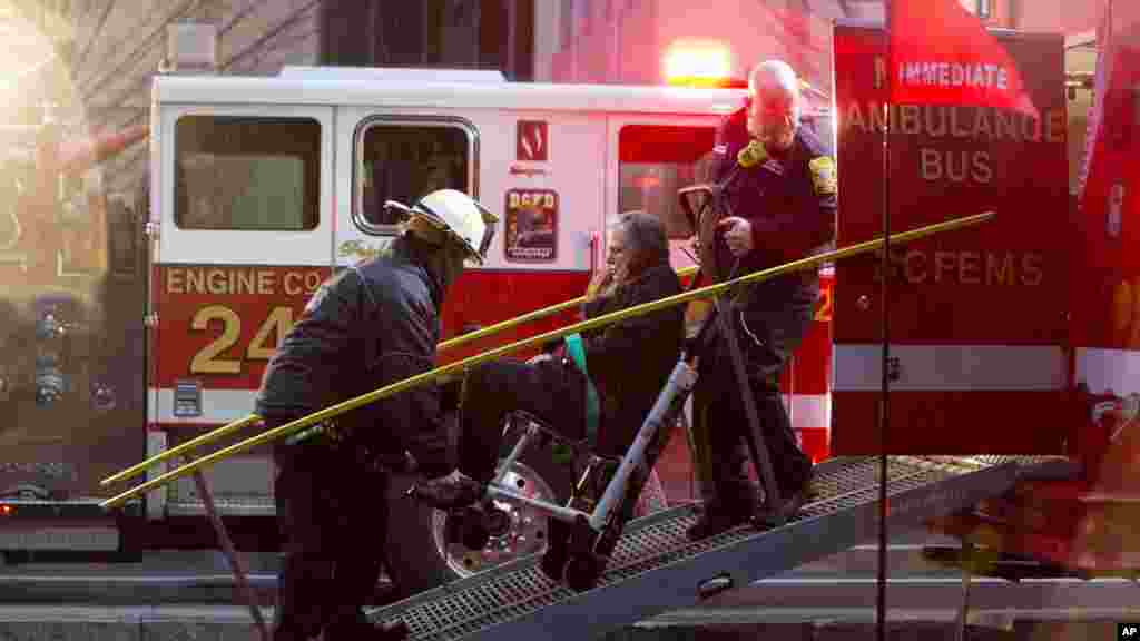 Une femme est transportée dans un fauteuil roulant à un bus d'ambulance où sont conduits les personnes évacuées d'un tunnel de métro de métro enfumée à Washington, lundi 12 janvier, 2015.