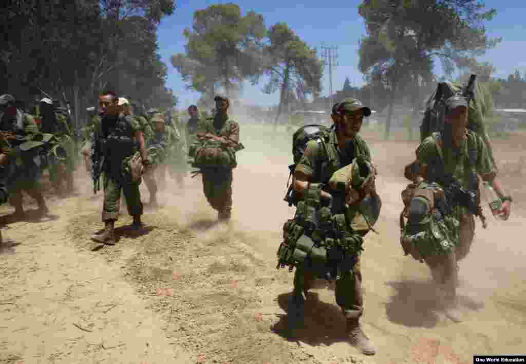 Israeli soldiers walk towards a staging area outside the Gaza Strip, July 18, 2014.