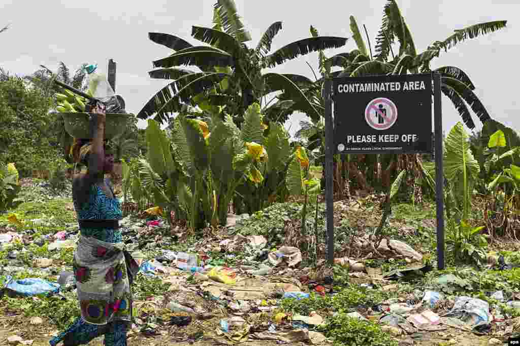 Wata mace tana wucewa jikin wani allon dake gargadi game da gurbacewar kasa a yankin al'ummar Ogale dake Niger Delta mai arzikin man fetur, 9 Maris 2016.