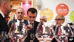 FILE - French President Emmanuel Macron drinks wine during a visit to the International Agriculture Fair (Salon de l'Agriculture) at the Porte de Versailles exhibition center in Paris, Feb. 22, 2020.