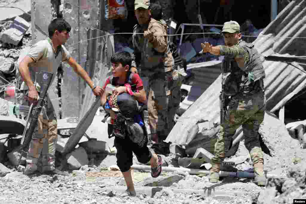 Seorang anak laki-laki yang mengungsi dari Mosul melewati posisi pasukan keamanan Irak di distrik al-Zanjili, Mosul barat.