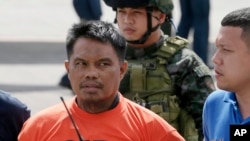 Army and police forces escort a handcuffed Mohammad Ali Tambako, the leader of a Muslim rebel group in the south who has been linked to bombings and a beheading and accused of protecting two terror suspects wanted by the United States, shortly upon arriva