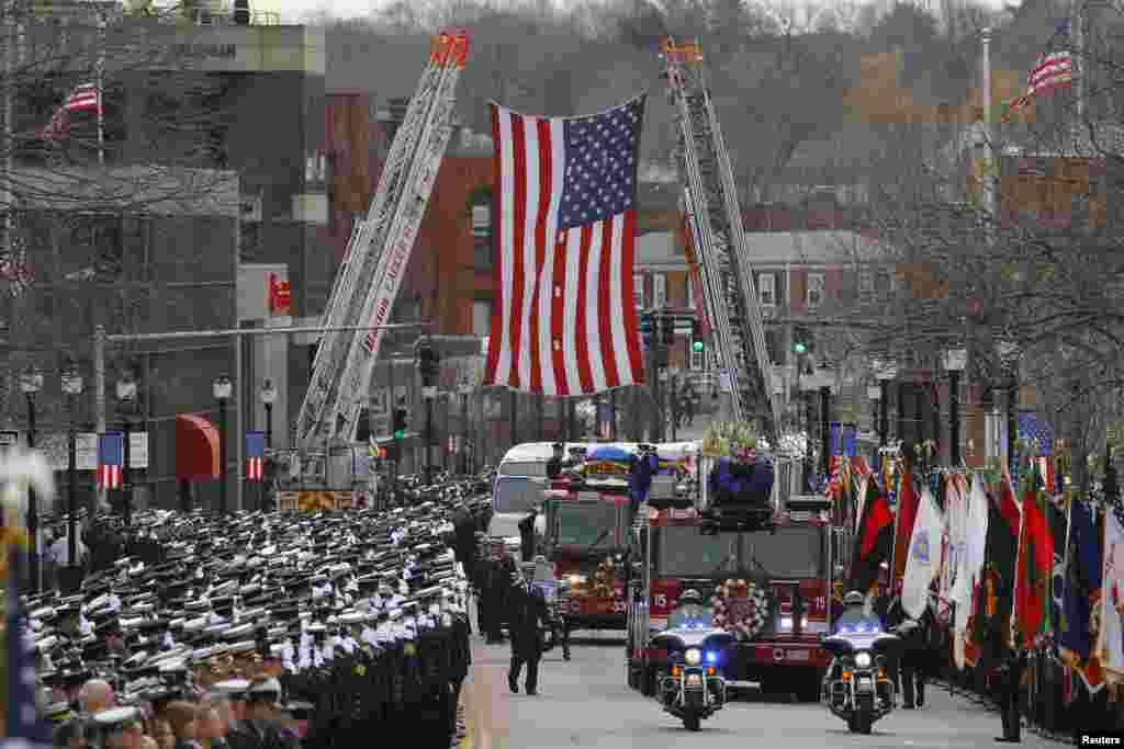 A fire engine carries the body of Boston Fire Department Lieutenant Edward Walsh to his funeral at Saint Patrick's Church in Watertown, Massachusetts, April 2, 2014. Thousands of firefighters from across the United States lined the streets for the funeral of Walsh, one of two firefighters who died battling a blaze in a Boston apartment building last week.