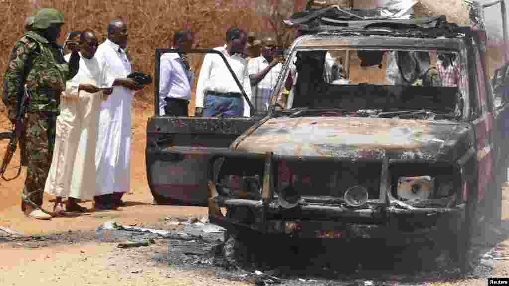 Des agents de sécurité et des membres du gouvernement inspectent une voiture de police qui a été brûlée lors d'une attaque contre un convoi escortant le gouverneur de la région de Mandera Ali Roba près de la ville de Mandera, 13 Mars 2015.