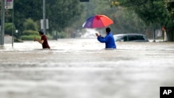 Moses Juarez, kiri, dan Anselmo Padilla mengarungi banjir dari Badai Tropis Harvey, 27 Agustus 2017 di Houston, Texas.