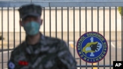 Seorang marinir Korea Selatan yang mengenakan masker berdiri di depan Pangkalan Angkatan Laut di Pulau Jeju, Korea Selatan, sebagai ilustrasi. (Foto: AP)