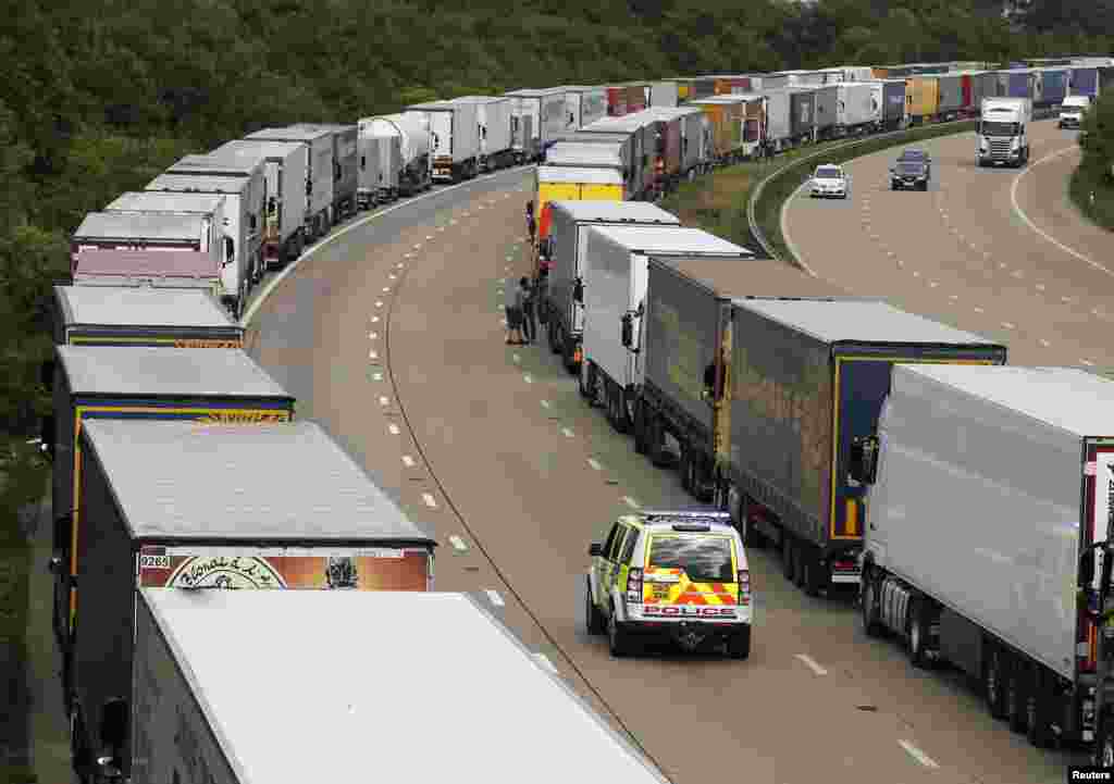 A police vehicle drives past trucks that are backed up on the M20 motorway which leads from London to the Channel Tunnel terminal at Ashford and the Ferry Terminal at Dover. The Channel Tunnel terminal and ferry port at Calais were both shut after industrial action by workers leading to all cross-Channel travel being stopped.